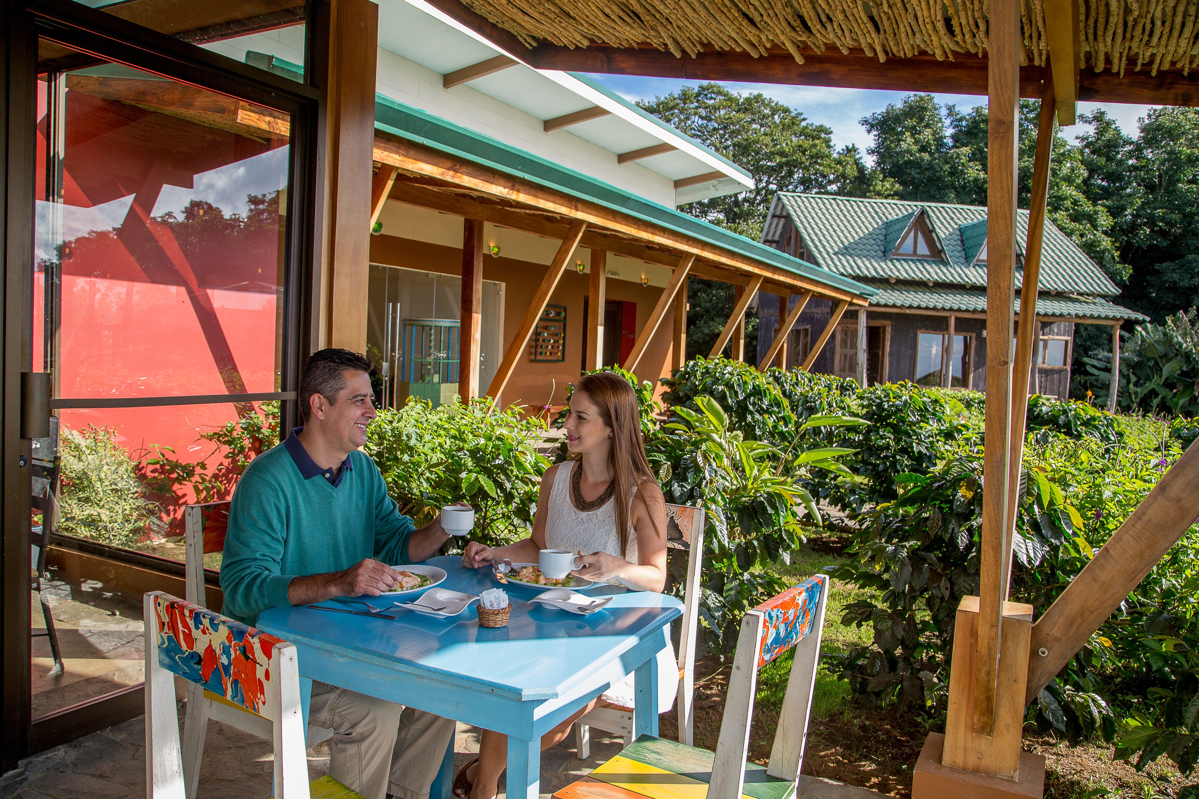 Zona pranzo con tavolo e sedie, una finestra e vista su una casa con tetto verde.
