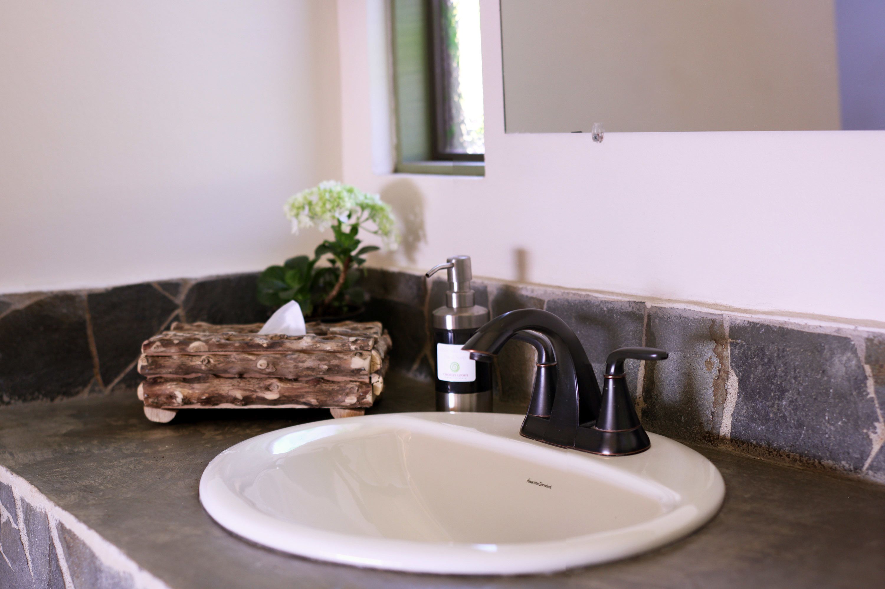 Un lavamanos de baño con un grifo moderno, una pileta blanca y un bloque de madera decorativo.