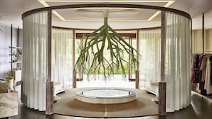 Una habitación circular con una planta colgante en el centro, una mesa redonda y un perchero.