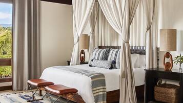 A bedroom with a canopy bed, a wooden ceiling, a nightstand, a lamp, and a view of greenery outside.