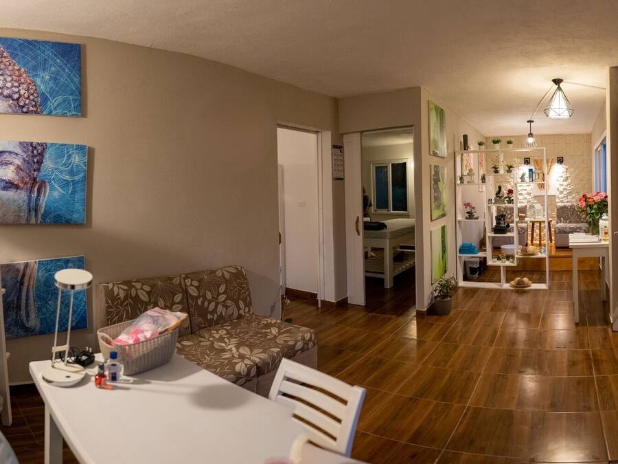 A spacious living area with a sofa, a dining table, and a kitchen in the background.