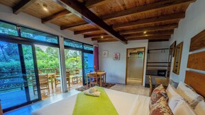 Un dormitorio con una cama grande, una colcha verde y vistas a un balcón con muebles de madera.
