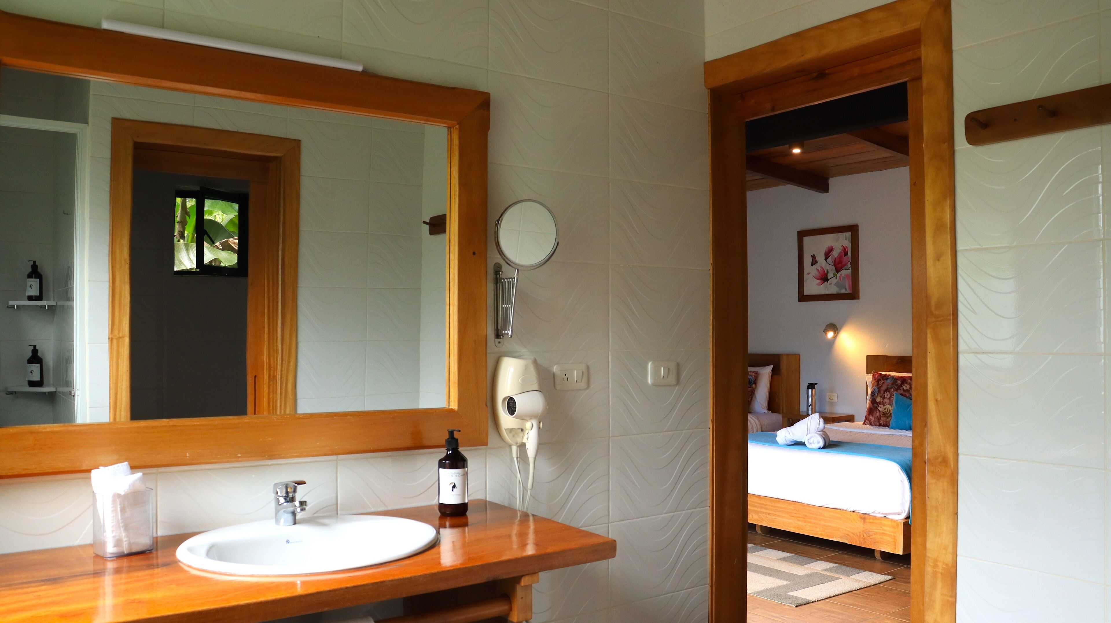 A bathroom with a wooden vanity, a large mirror, a hairdryer, and a sink.