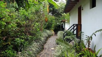 A narrow stone pathway leading to a white building with a wooden staircase.