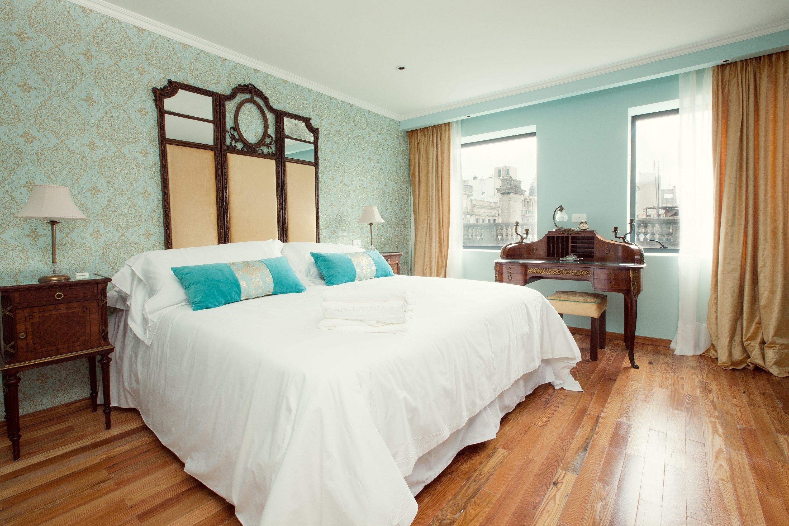 A hotel room with a large bed, a desk, and a view of the city.