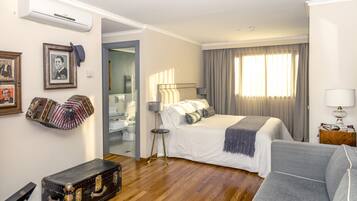 Una habitación de hotel con una cama, un sofá, una maleta y un espejo.