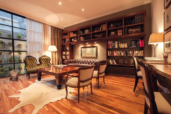 A cozy living room with a leather sofa, wooden coffee table, and bookshelves filled with books and decorative items. - Alma Histórica Boutique Hotel (Montevideo)