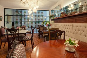 A dining area with a wooden table, chairs, and a tufted sofa. - Alma Histórica Boutique Hotel (Montevideo)