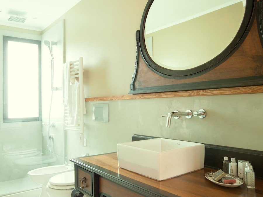 Ein Badezimmer mit einem Holzbadezimmer-Möbel, einem runden Spiegel, einem weißen Waschbecken und einer Toilette.