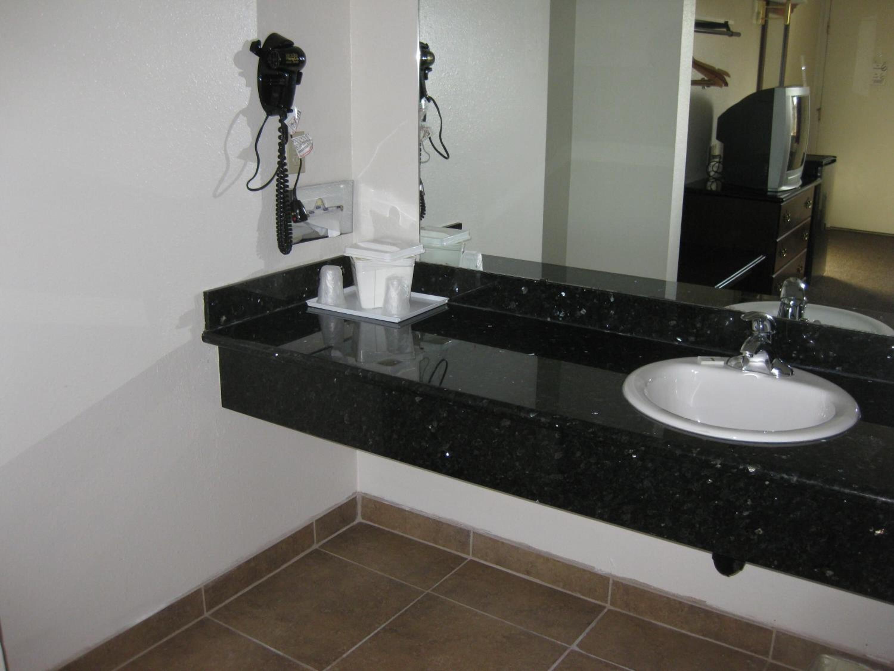 A bathroom with a black granite countertop, white sink, and a mirror above the sink.