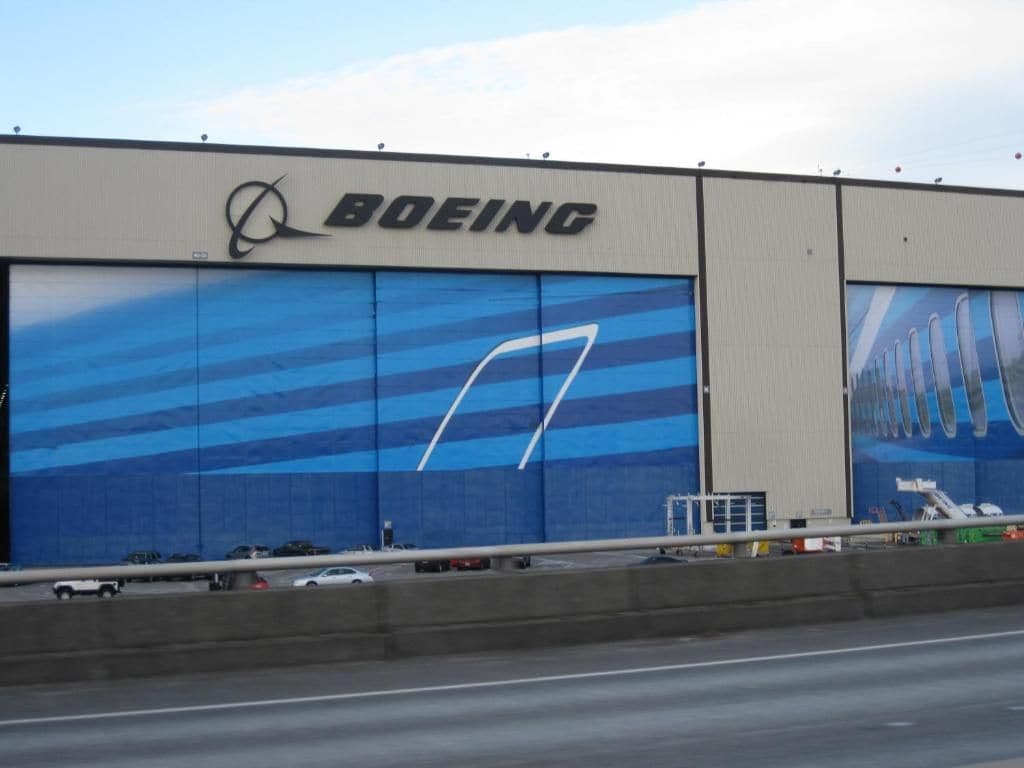 Un grande edificio industriale con il logo Boeing e un'ampia finestra blu.