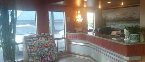 A reception area with a counter, a large window, and a wall-mounted painting.