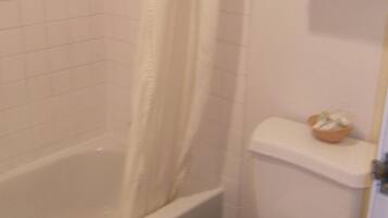 Un baño con bañera, inodoro y cortina de ducha.