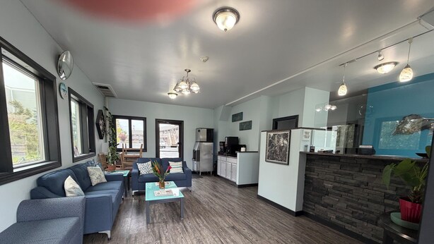 A modern living room with a sofa, coffee table, and kitchen area with appliances. - Hyannis Host Inn (Hyannis)