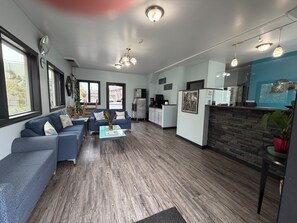 A modern living room with a sofa, coffee table, and kitchen area with appliances.