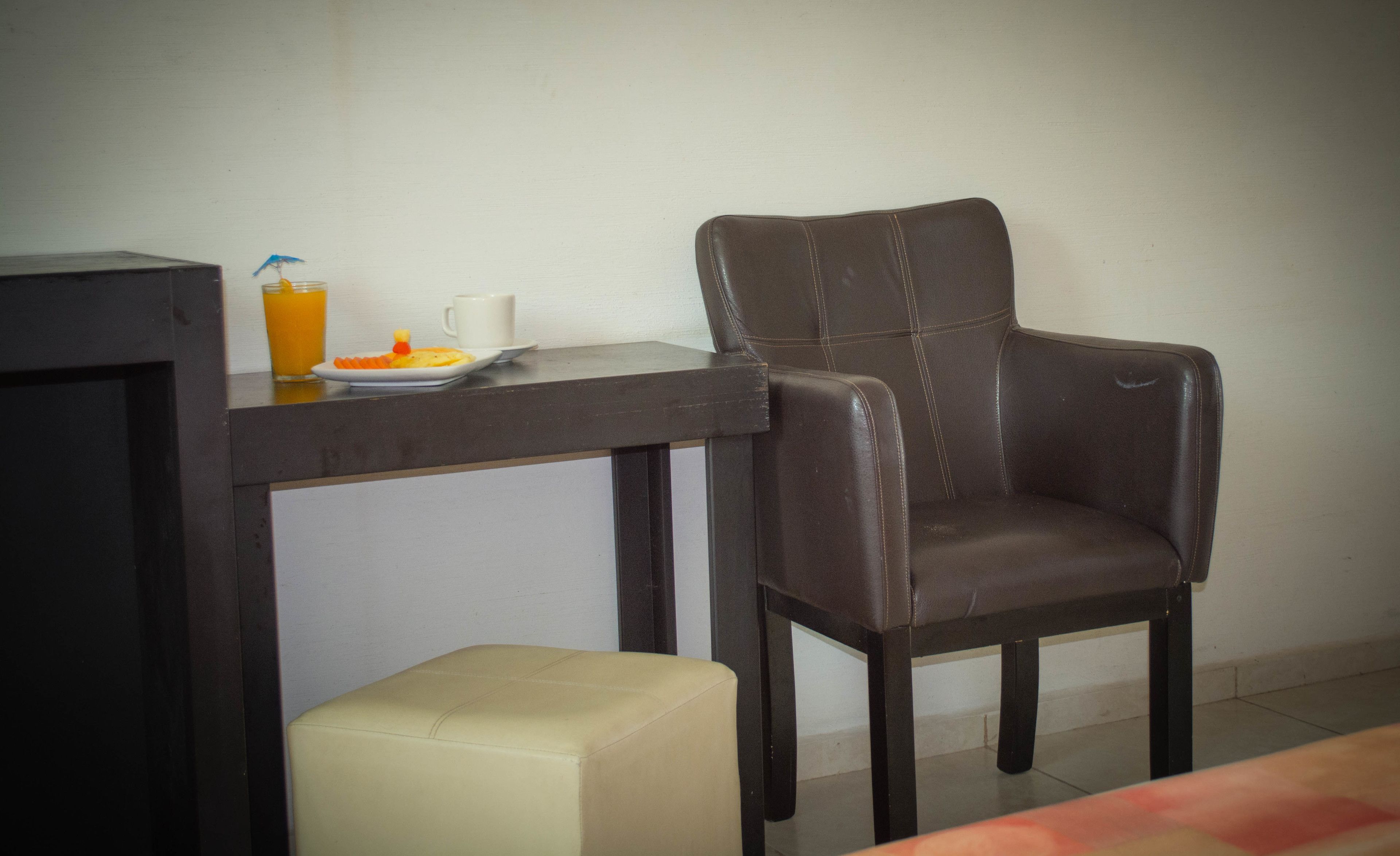 A dining area with a dark brown leather chair, a small white table, and a white cushioned bench.