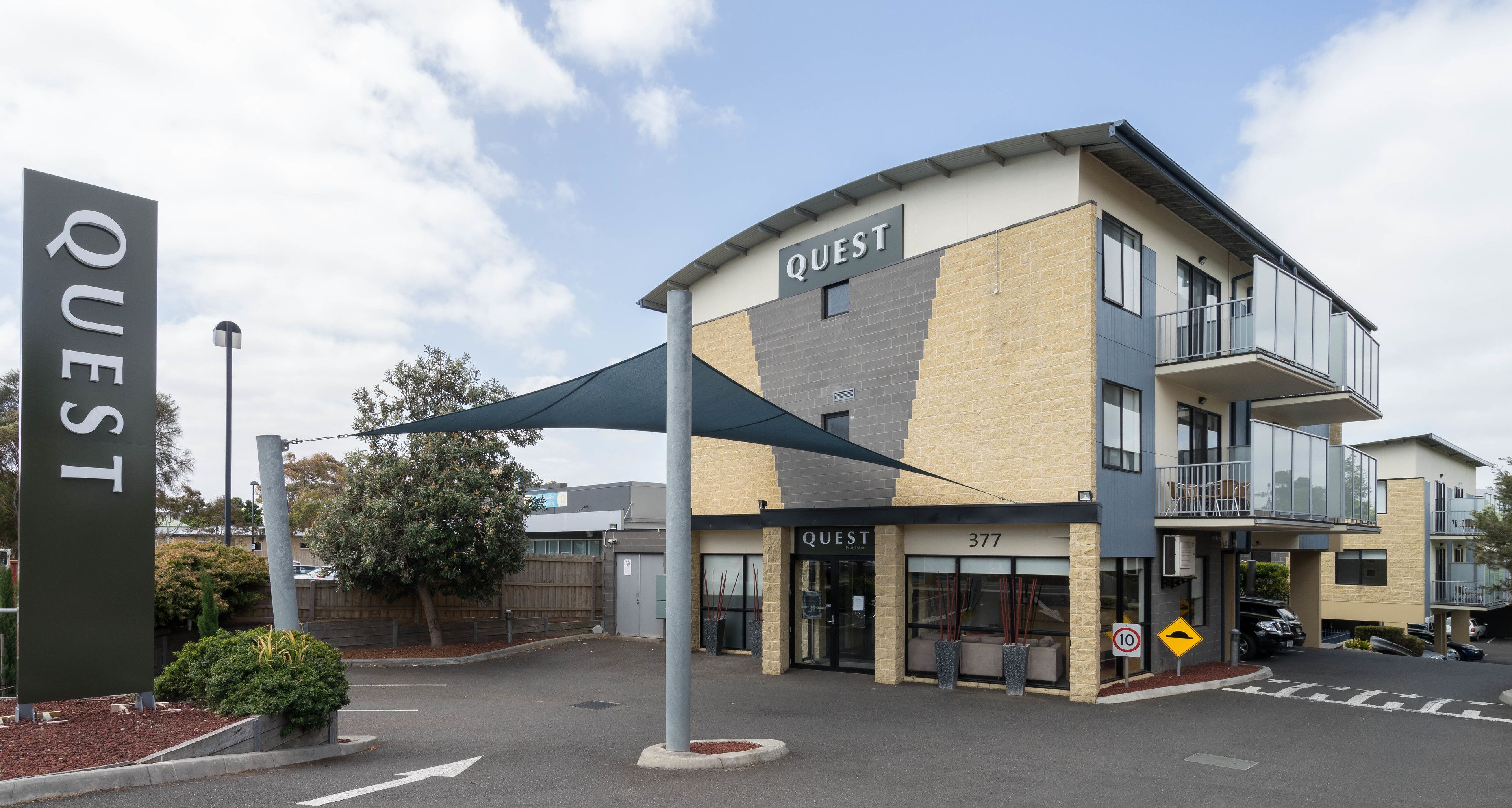 A modern building with a sign reading "QUEST" and the number "377" on the facade.