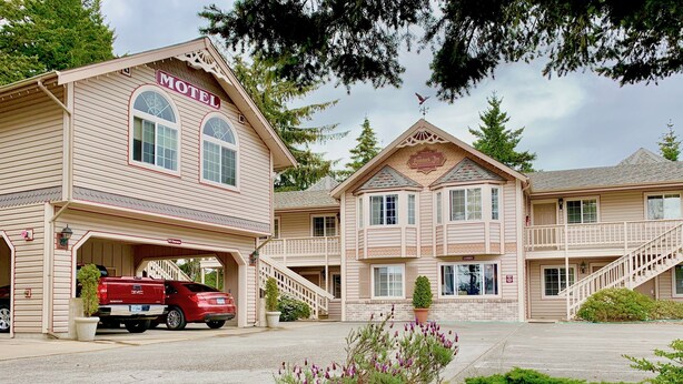 A motel with a two-story structure, a covered parking area, and a red truck parked outside. - Landmark Inn (Florence)