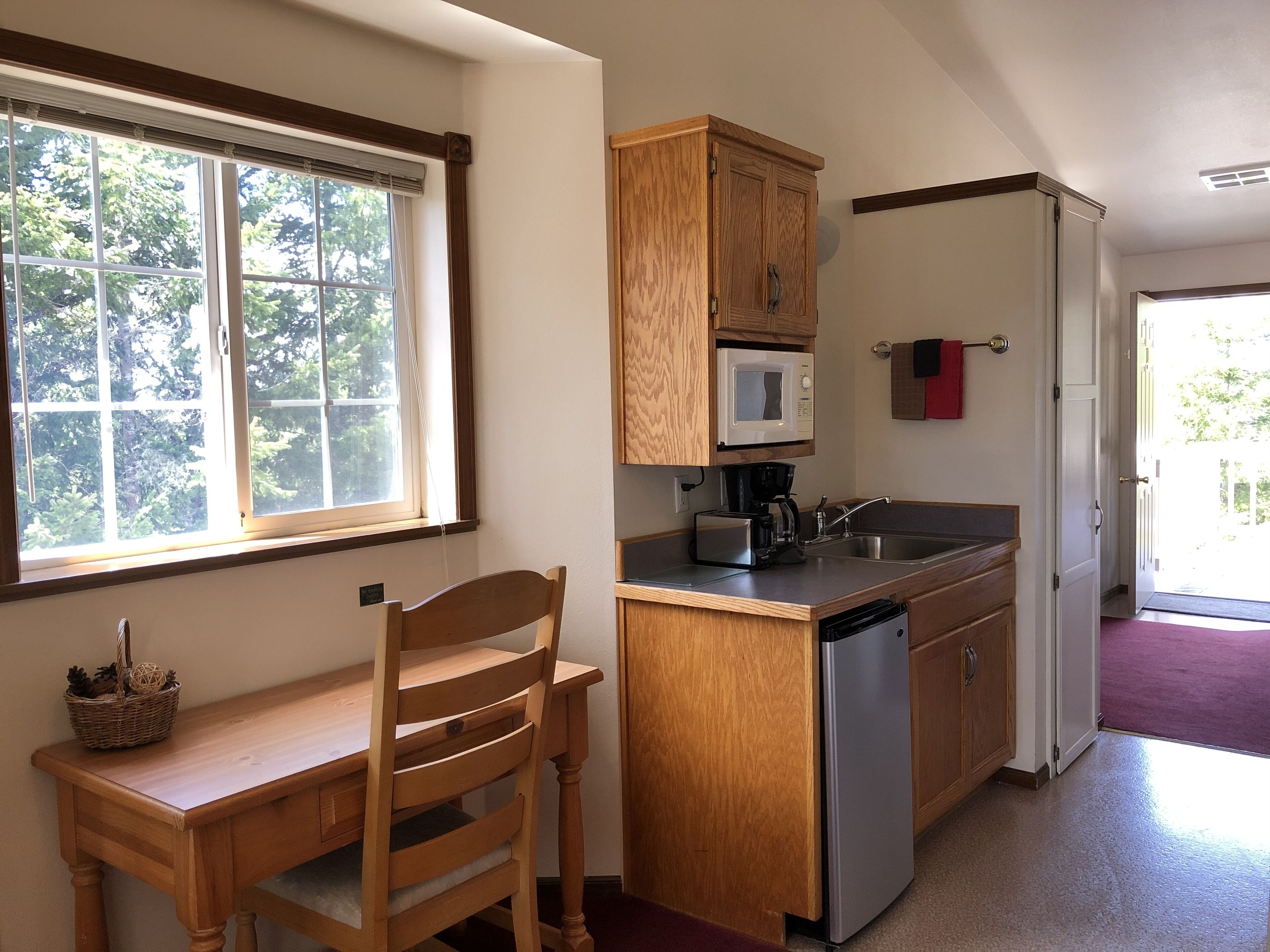 A compact kitchen with wooden cabinets, a microwave, a coffee maker, and a dishwasher.