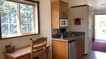 Una cocina compacta con armarios de madera, microondas, cafetera y lavavajillas.