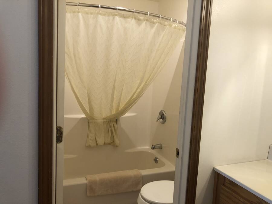 A bathroom with a bathtub, toilet, and a shower curtain.