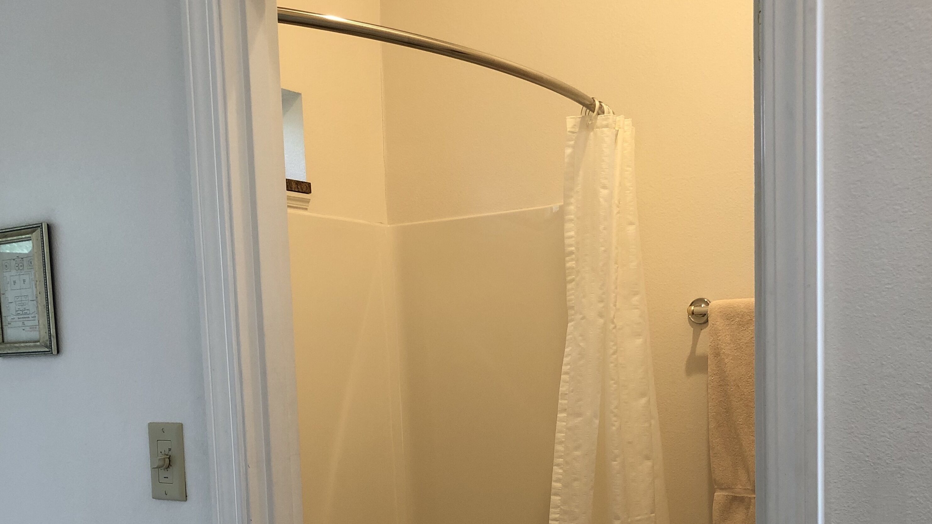 A bathroom with a shower, a towel rack, and a framed picture on the wall.