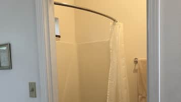 Un baño con ducha, toallero e imagen enmarcada en la pared.