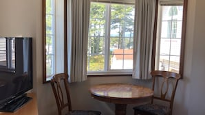 A hotel room with a television, a wooden table with two chairs, a bed, and a window with curtains. - Landmark Inn (Florence)