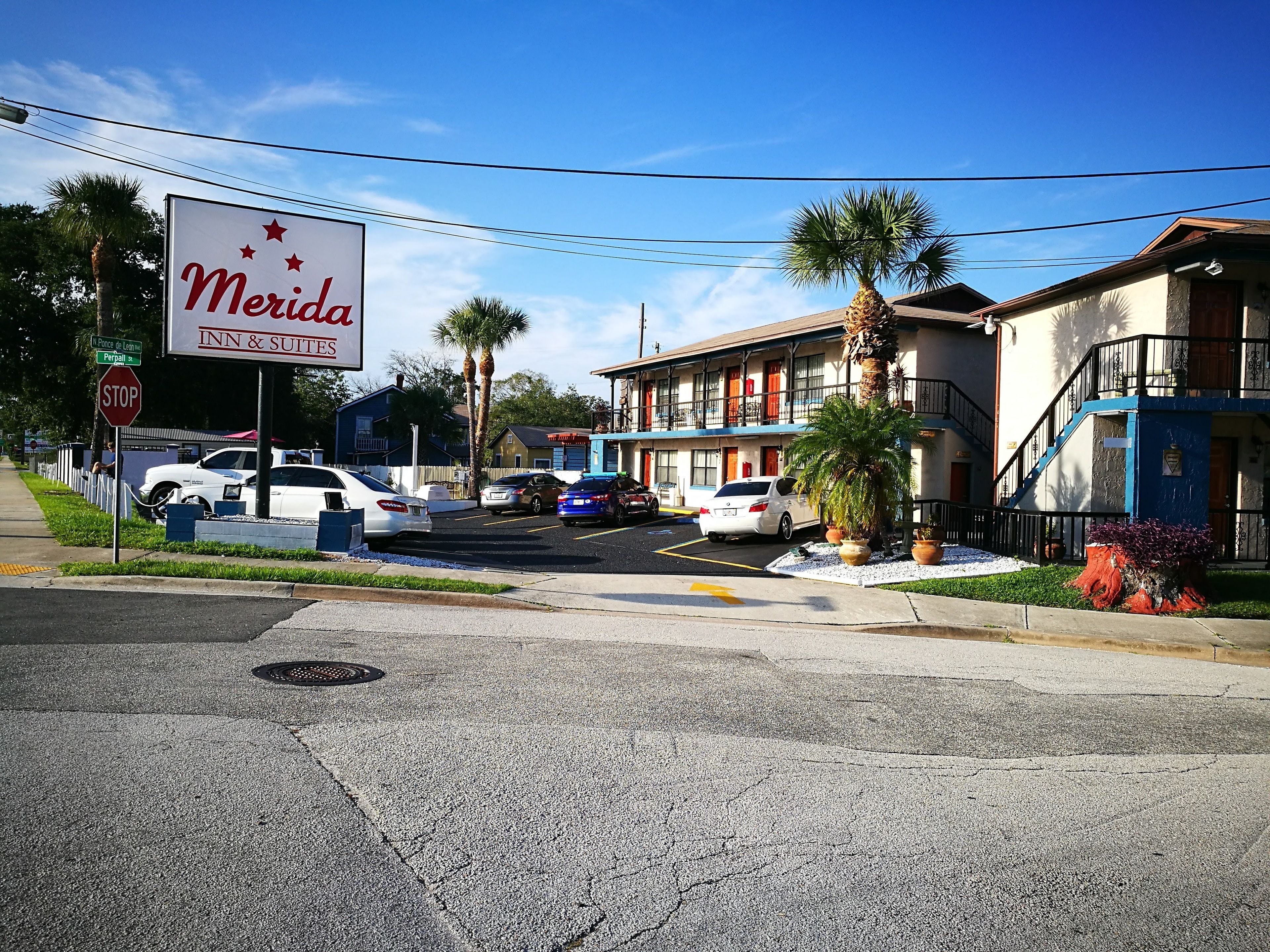 A street view with a motel named 'Merida Inn & Suites' and a stop sign.