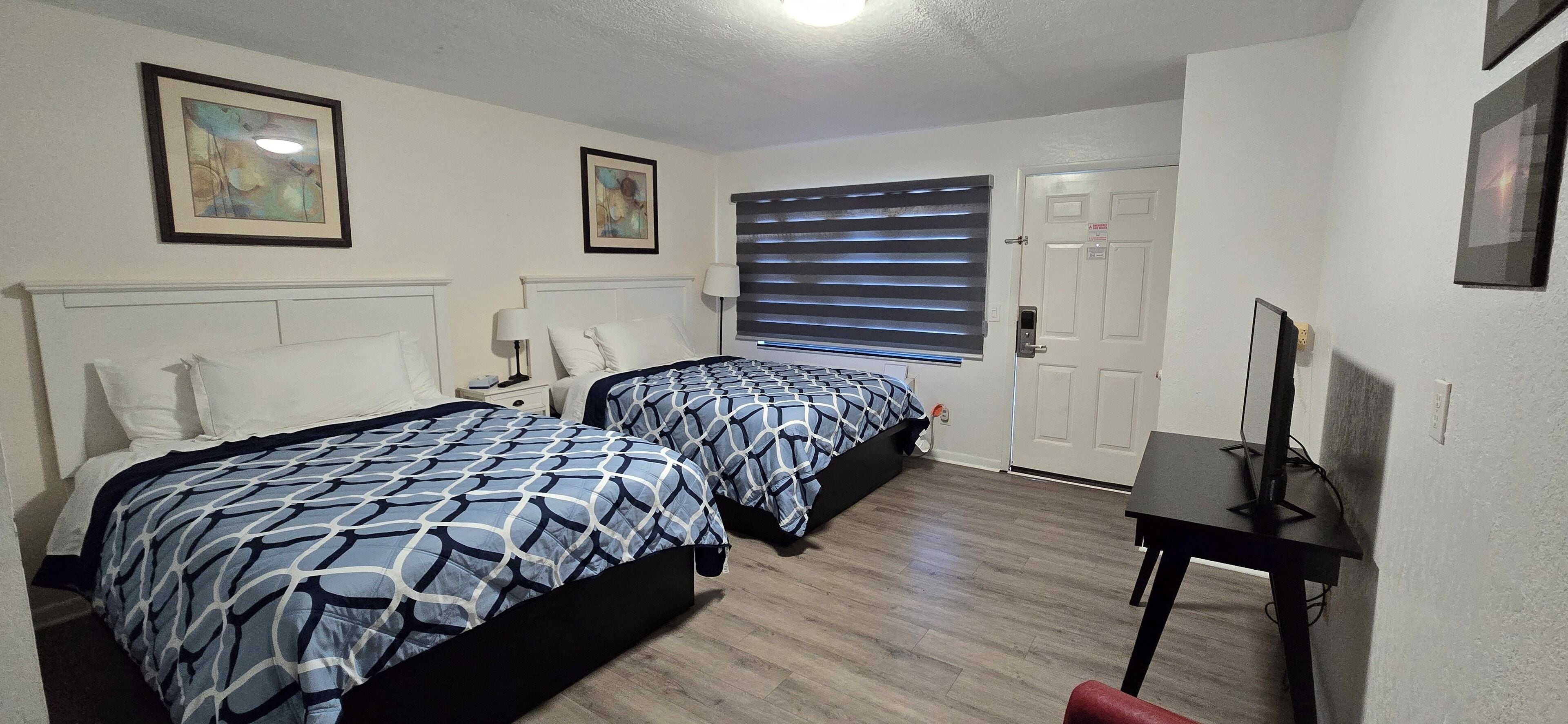 A hotel room with two beds, a desk, and a TV.