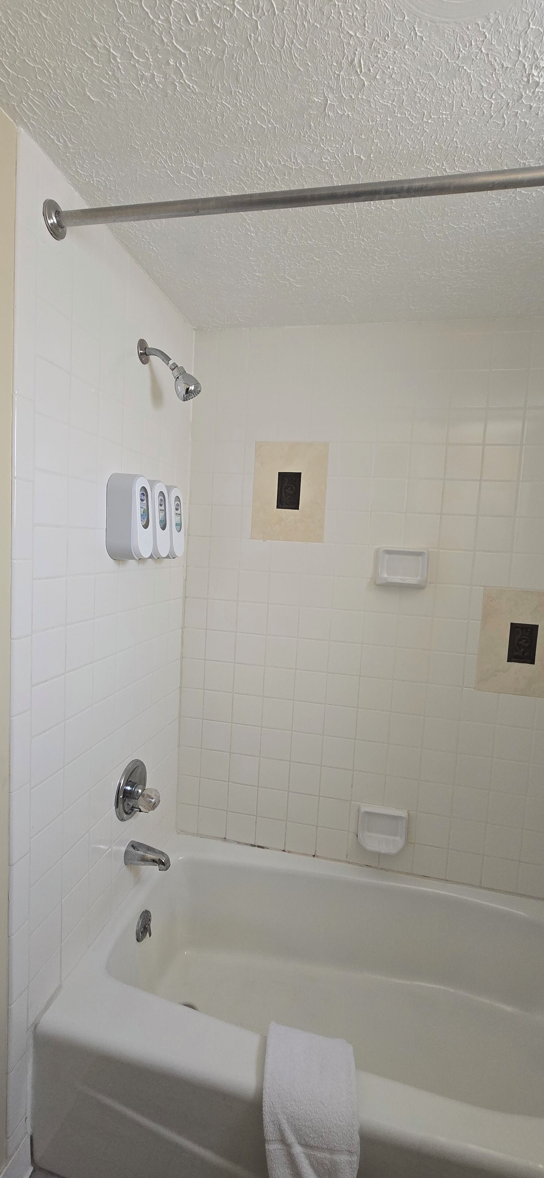 A bathroom with a bathtub, a showerhead, and a hand dryer.
