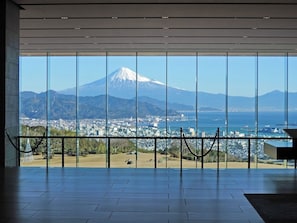 A room with large windows offering a view of a cityscape and a mountain.