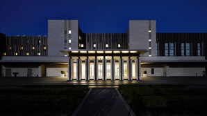 Un edificio moderno con fachada simétrica, ventanas amplias y una entrada central con columnas.