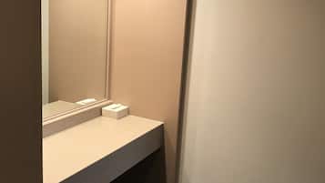 A small, private bathroom with a sink, mirror, and a chair.