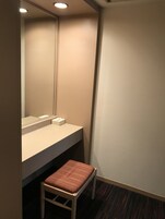 A small, private bathroom with a sink, mirror, and a chair.