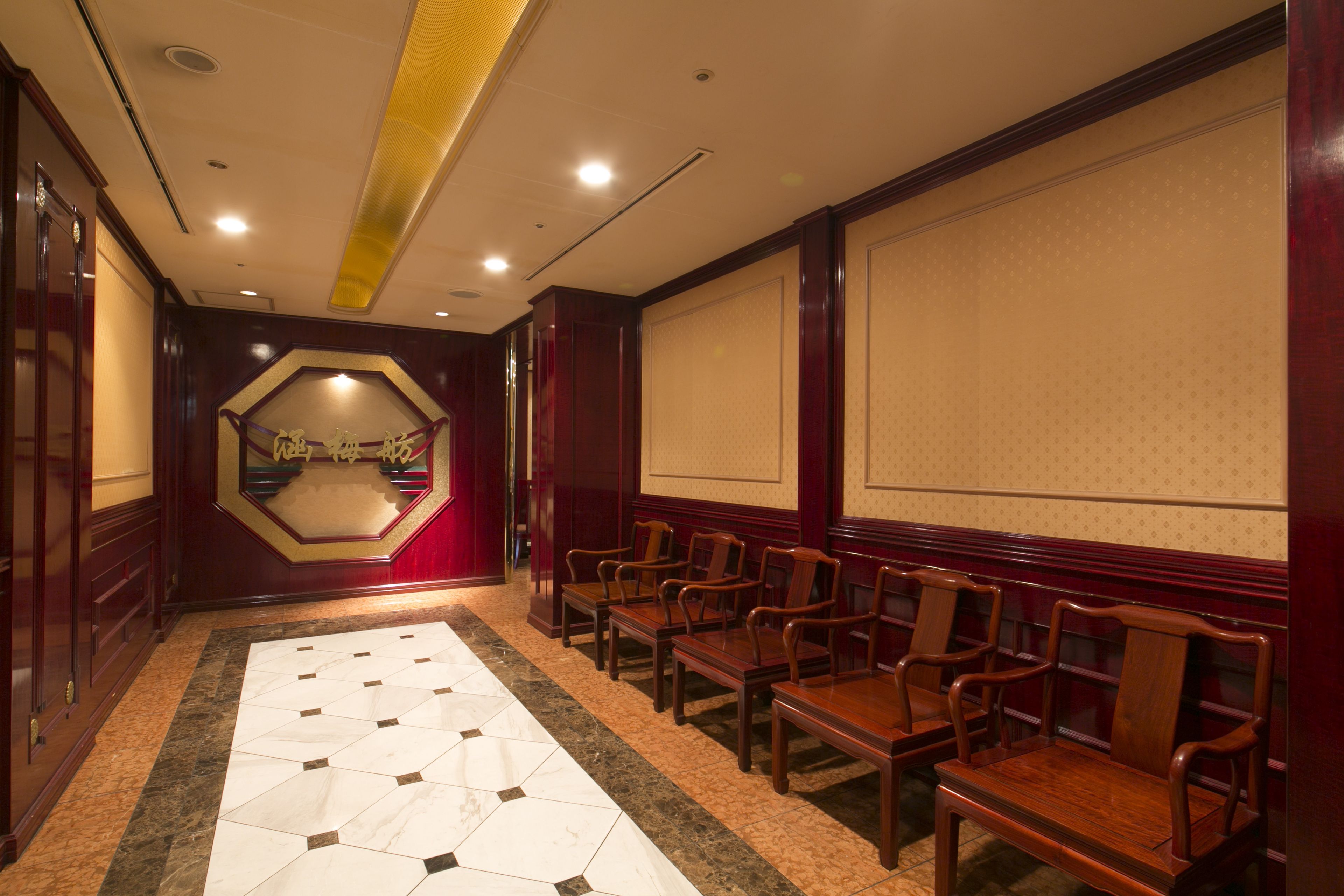 Una sala de conferencias con piso de baldosas, sillas de madera, una pantalla grande y un panel de pared de madera.