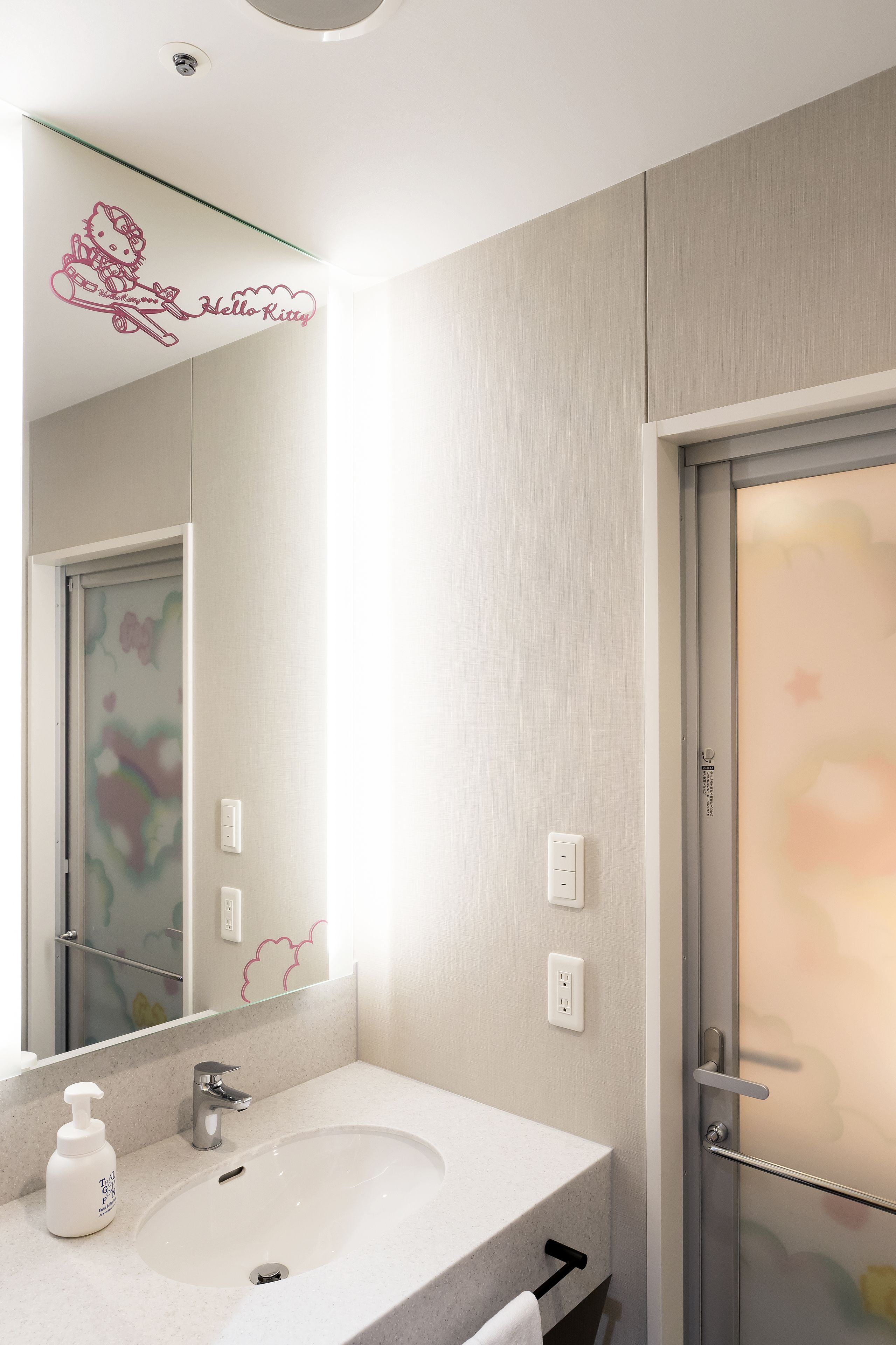 A modern bathroom with a large mirror, a white sink, and a glass shower enclosure.
