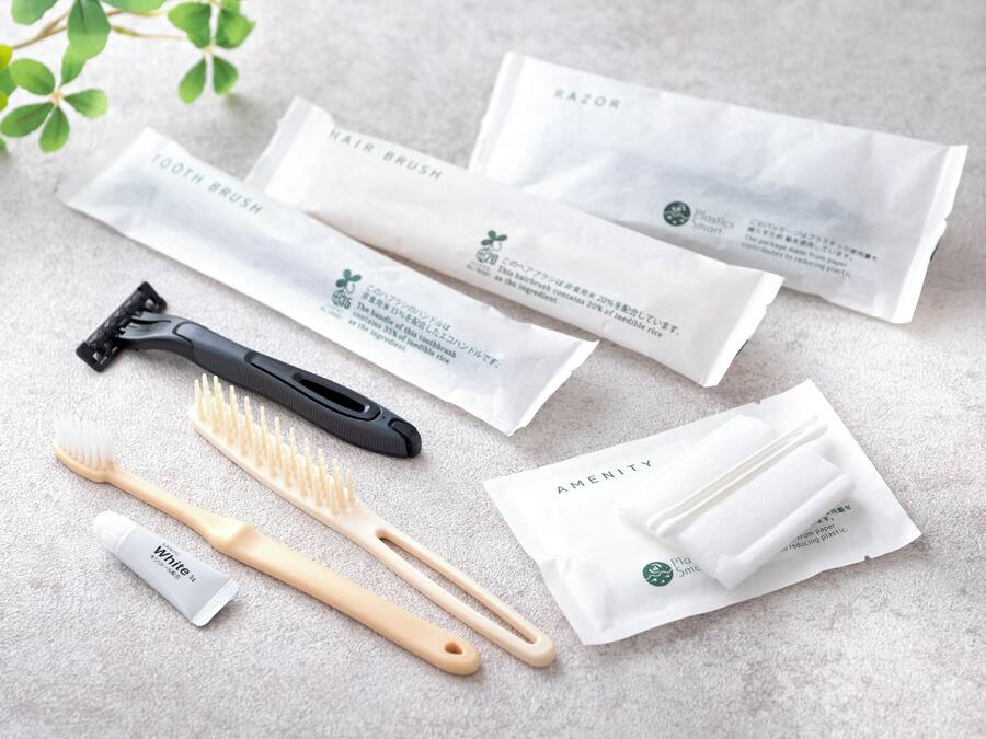 Un conjunto de artículos de aseo personal que incluye un navaja, un cepillo para el cabello y un cepillo de dientes, junto con sus respectivos empaques.