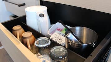 Uma gaveta de cozinha com diversos utensílios e recipientes, incluindo uma cafeteira, uma panela de metal e potes de tempero.