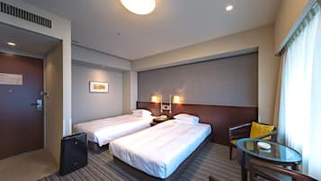 A hotel room with two beds, a desk, a chair, and a small table.