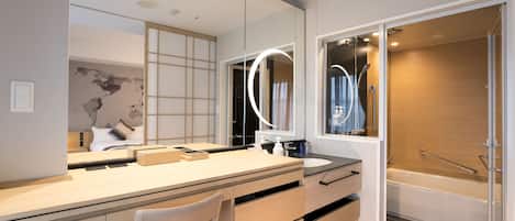 Un baño moderno con un espejo grande, un lavamanos y una zona de ducha.