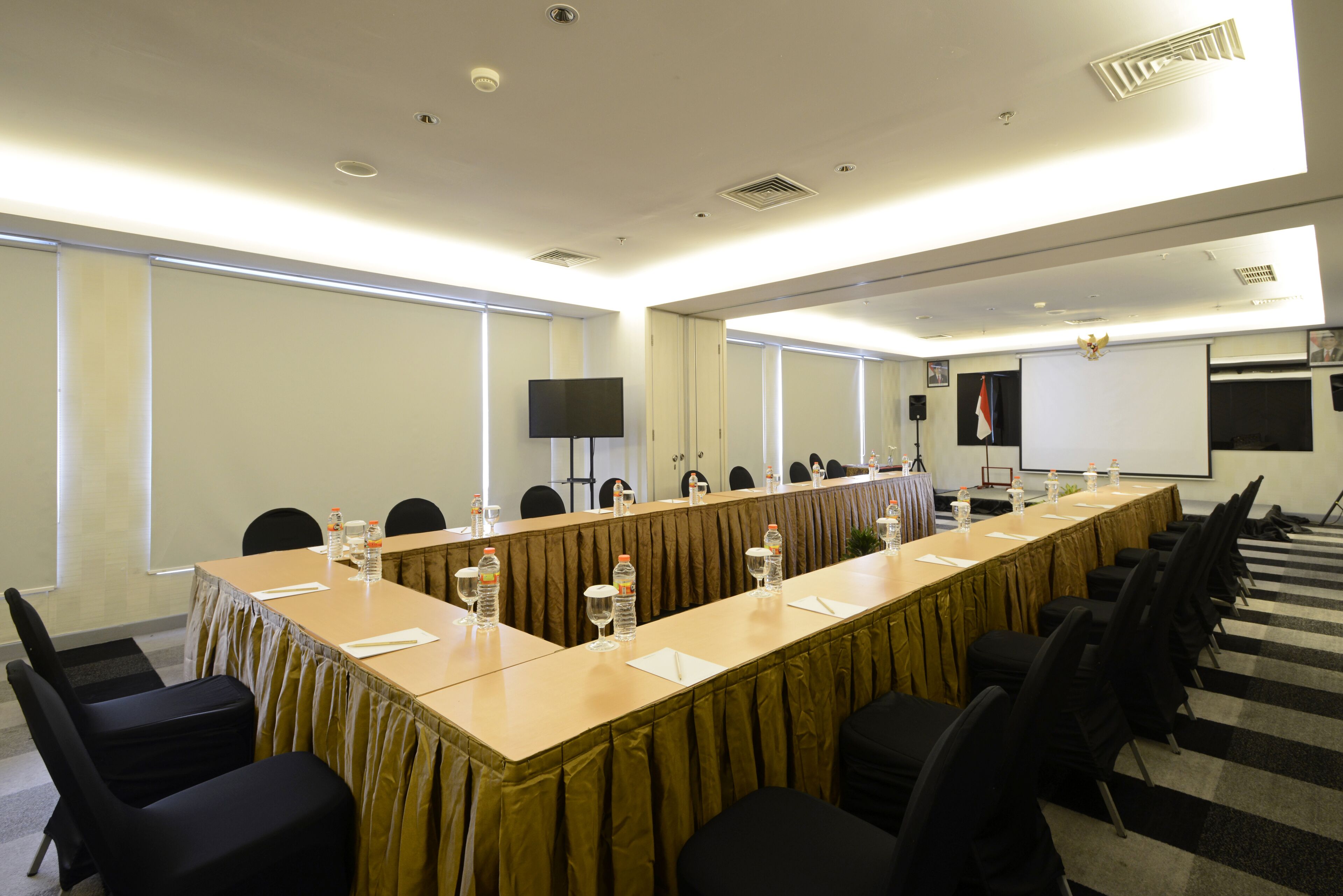 A conference room with a long table, chairs, a projector screen, and a whiteboard.