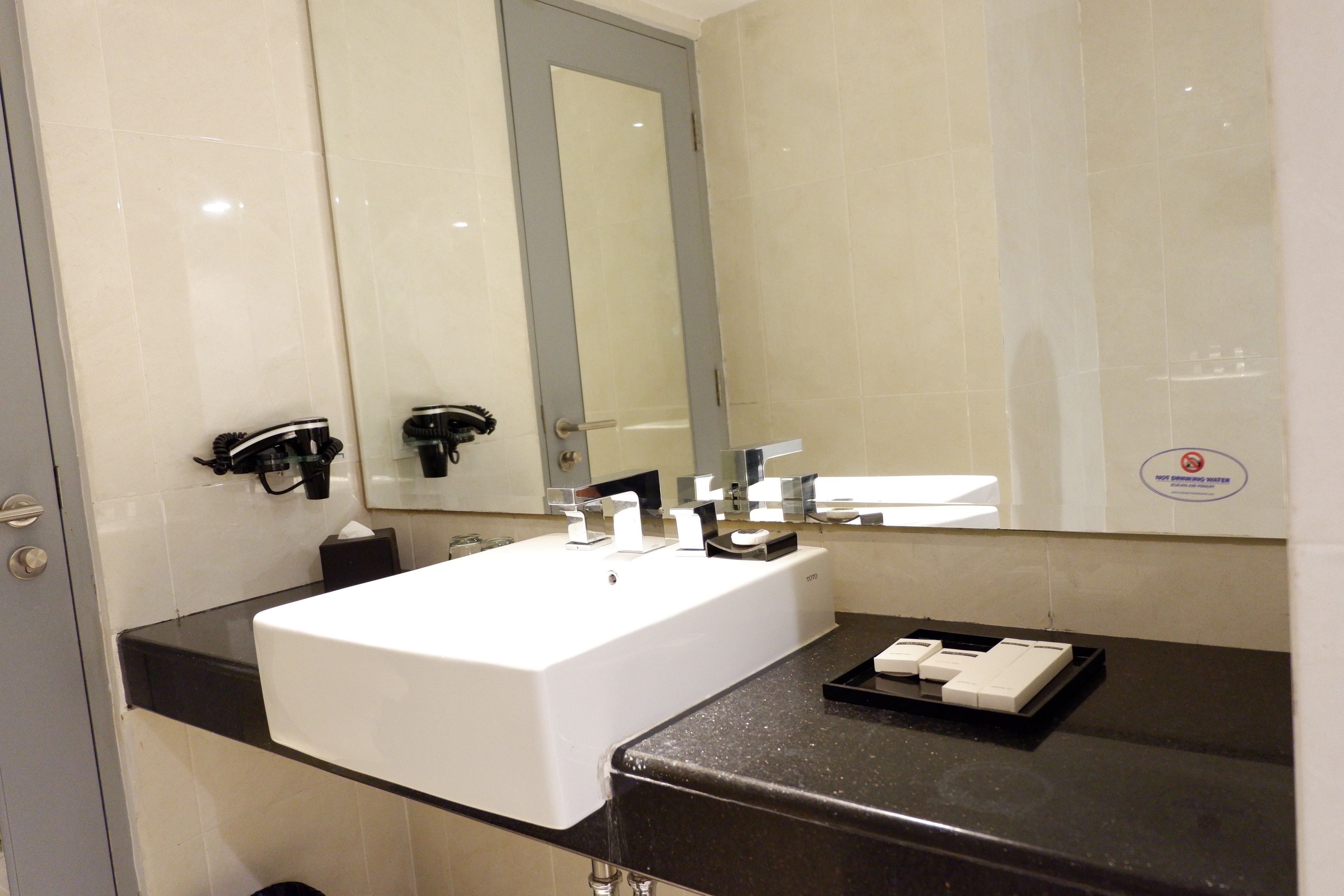 Un bany modern amb un lavabo blanc, tauleig negre i un gran mirall.