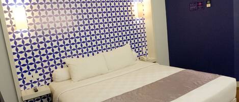 Uma cama bem arrumada com cabeceira estampada, uma mesa de cabeceira com controle remoto e uma parede com padrão geométrico.