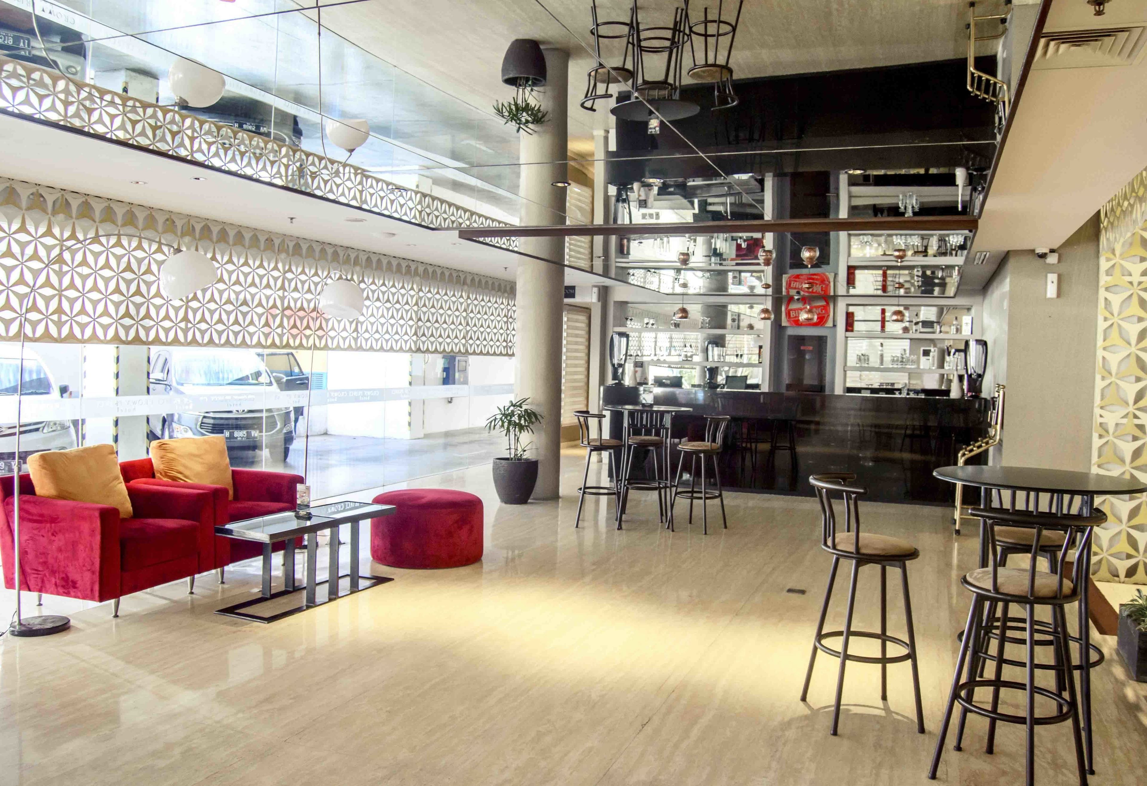 A modern interior with a red sofa, a round ottoman, and a bar area with stools.