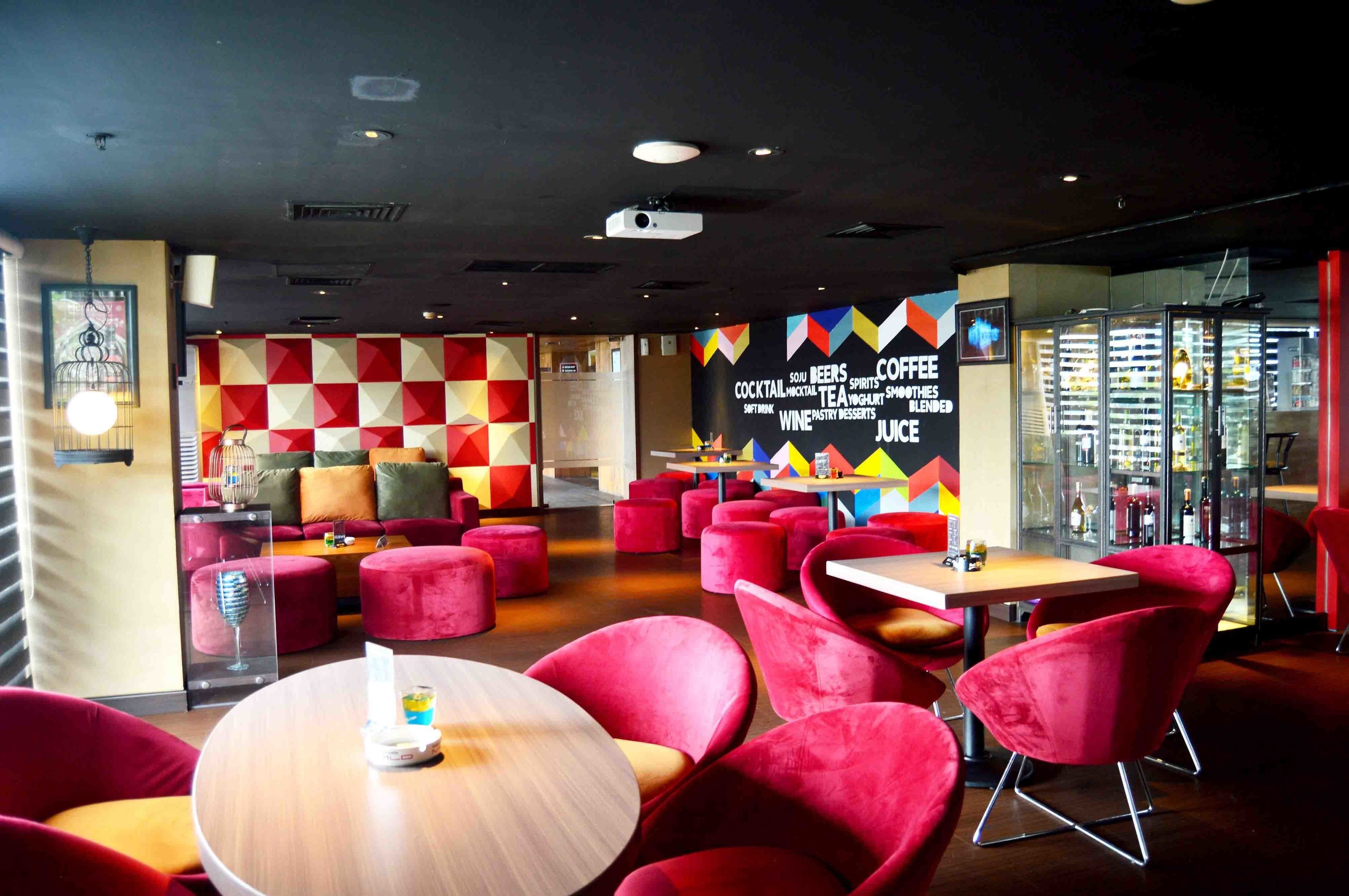 A modern cafe interior with red seating, a blackboard menu, and a glass display case.
