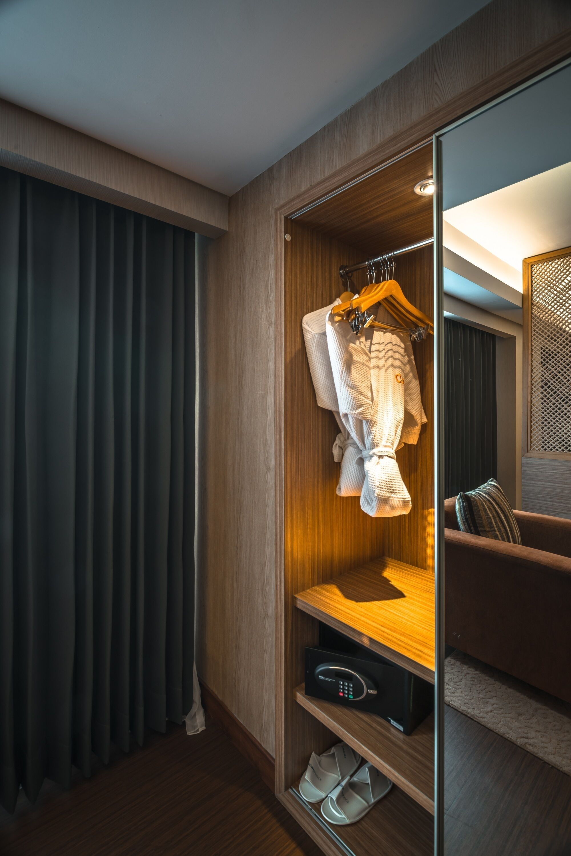 Ein modernes Hotelzimmer mit einem Holzschrank, einem Spiegel und einer Sitzecke mit Kissen.