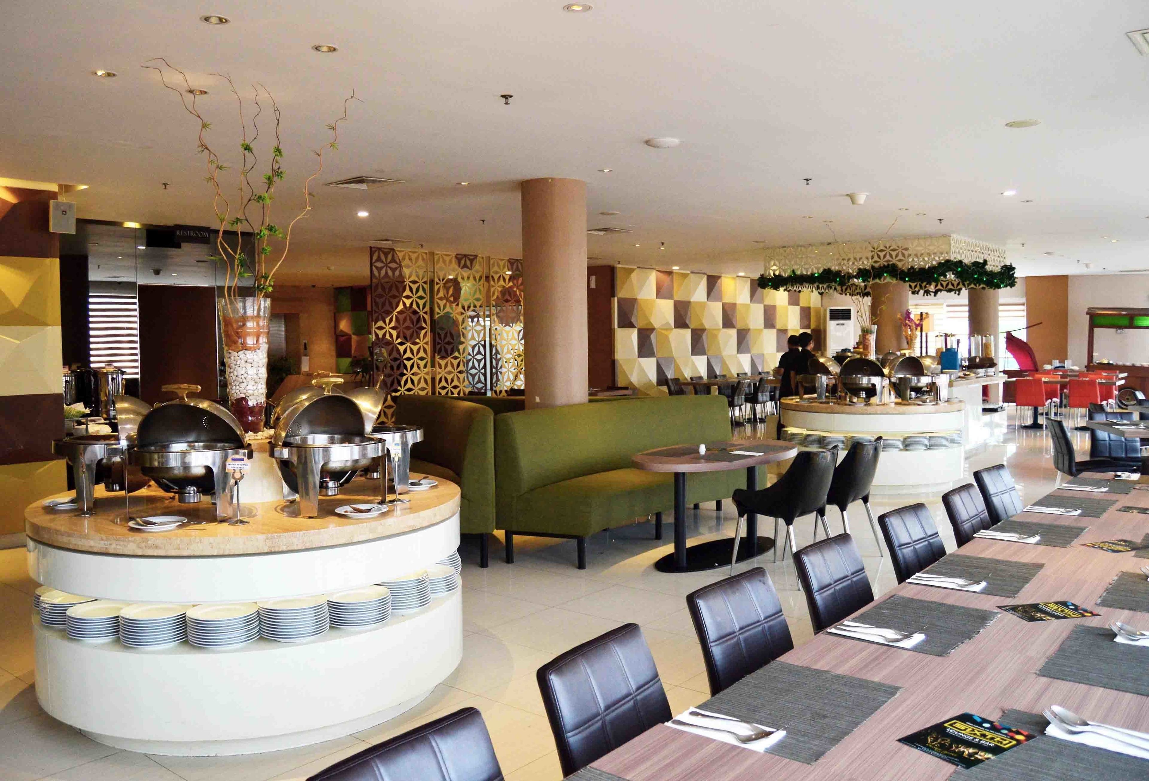 A hotel lobby with a buffet area, seating arrangements, and a decorative wall.