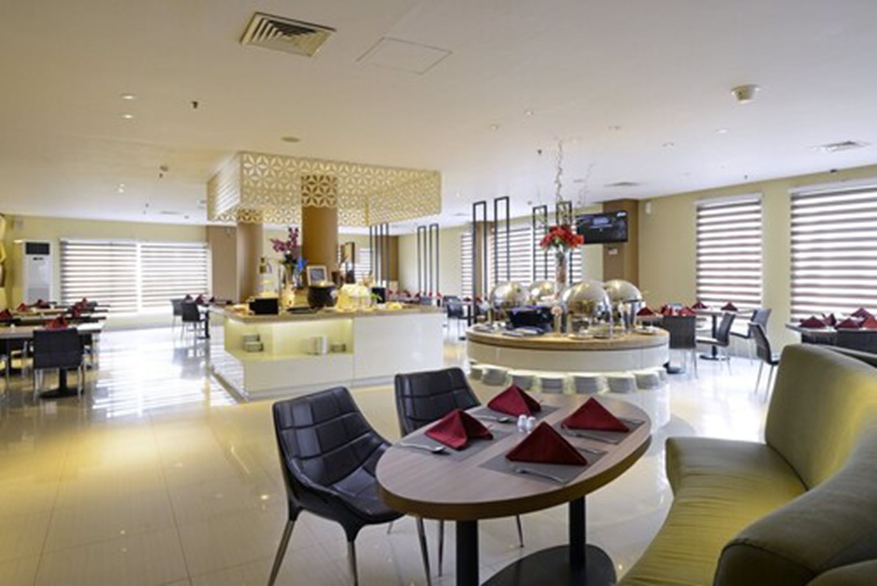 A spacious hotel lobby with a central bar area, multiple seating arrangements, and large windows.