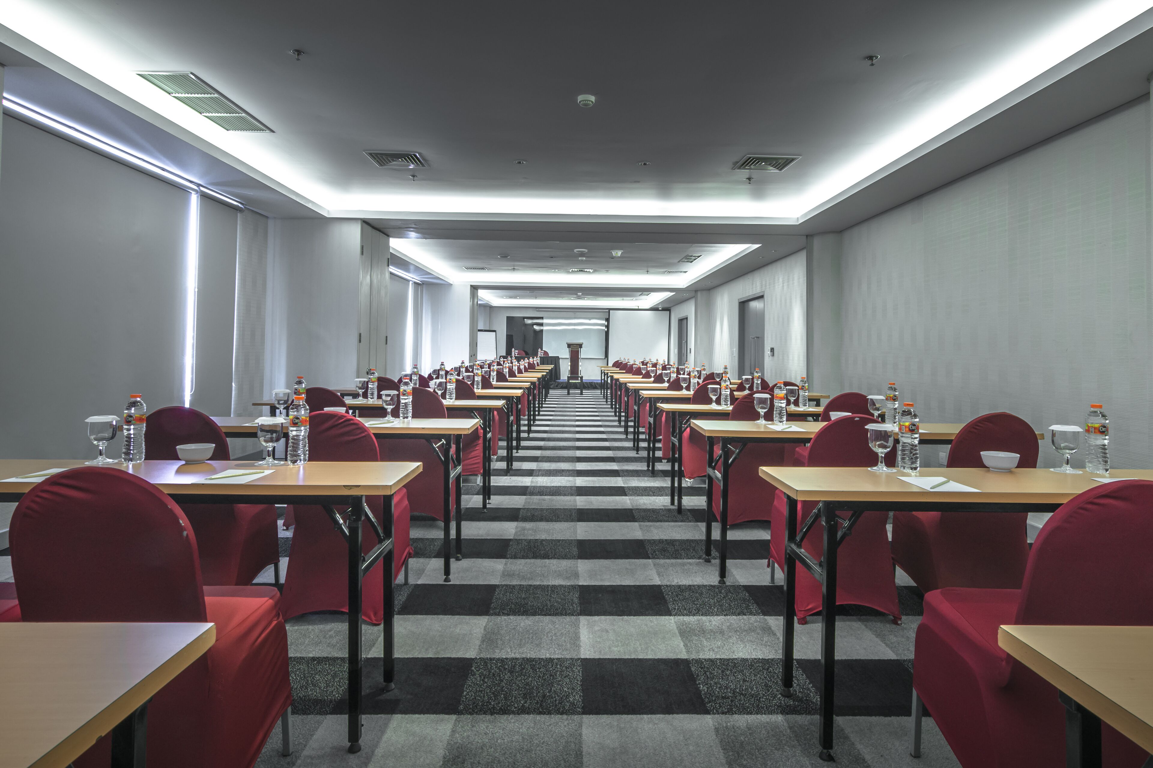 A conference room with rows of tables and chairs, equipped with water bottles and documents.